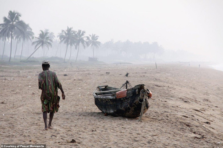 Người đàn ông đi bộ trên bãi cát vào buổi sáng ở Benin, một quốc gia Châu Phi.