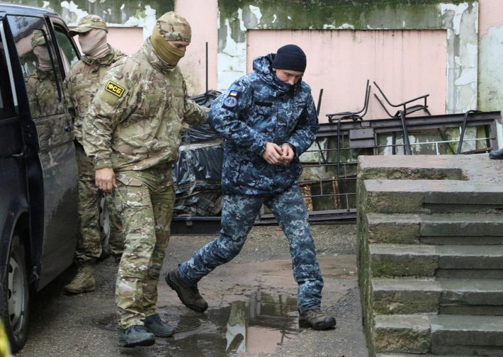 Một thành viên của Cơ quan An ninh Liên bang Nga (FSB) áp giải một thủy thủ Ukraine bị bắt giữ trước phiên tòa ở Simferopol, Crimea, ngày 27/11. Ảnh: Reuters.