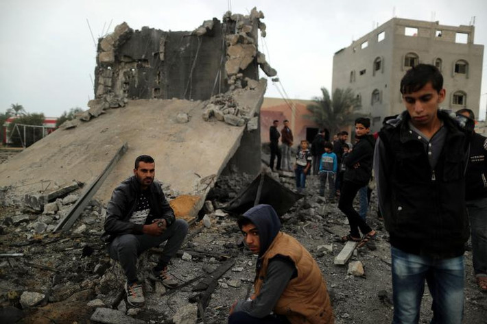 Người dân Palestine ngồi trên đống đổ nát của một tòa nhà bị phá hủy trong đợt không kích của Israel ở Khan Younis ngày 12/11. Ảnh: Reuters.