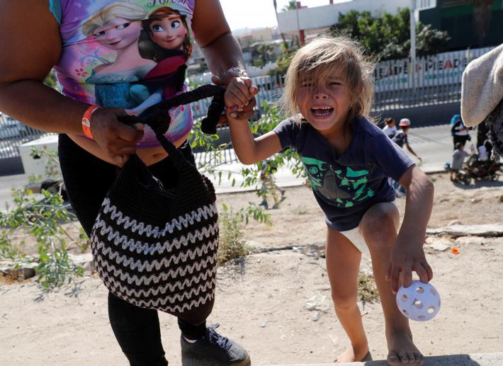 Một bé gái đến từ Honduras bật khóc gần bức tường biên giới ở Tijuana, Mexico, ngày 25/11.