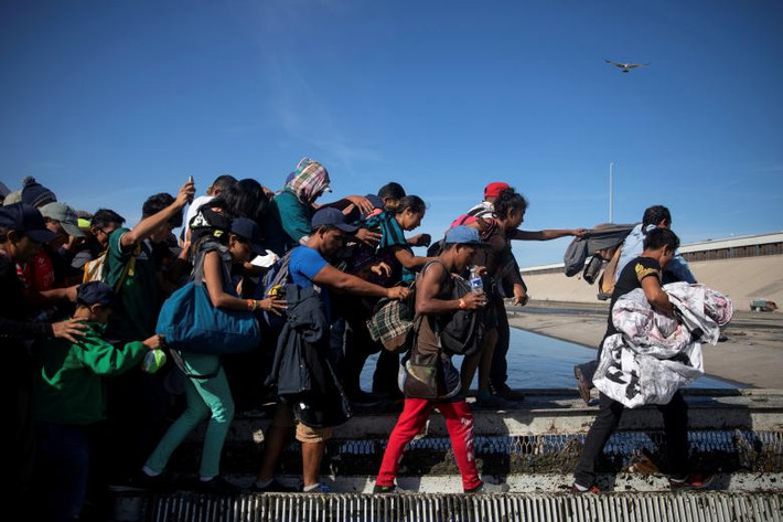 Các di dân vượt qua sông Tijuana để đến bức tường biên giới Mỹ-Mexico.