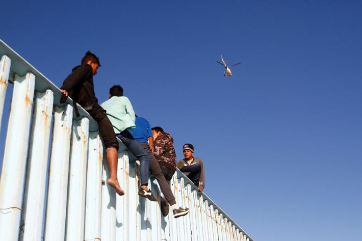 Một số di dân trèo lên hàng rào biên giới sau khi tới Tijuana, Mexico, hôm 13/11.