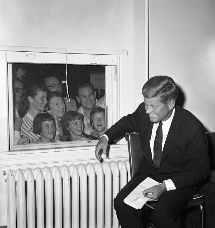 Ông Kennedy xem lại những tờ giấy ghi chú của mình trước khi có bài phát biểu tại bữa tối gây quỹ ở Baltimore, bang Maryland, ngày 16/9/1960, trong khi mọi người đứng ngoài cửa sổ nhìn ông.