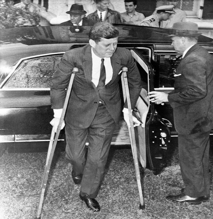 Tổng thống Kennedy chống nạng đi sau khi xuống chiếc limousine để lên du thuyền Honey Fitz du ngoạn trên sông Potomac với Thủ tướng Nhật Bản khi đó là Ikeda, tại Washington ngày 21/6/1961.