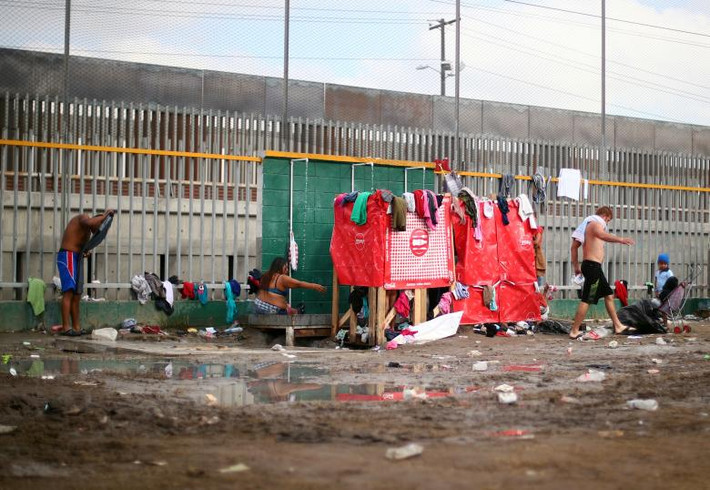 Một số di dân tắm gội ngay cạnh bức tường biên giới Mỹ-Mexico ngày 28/11.