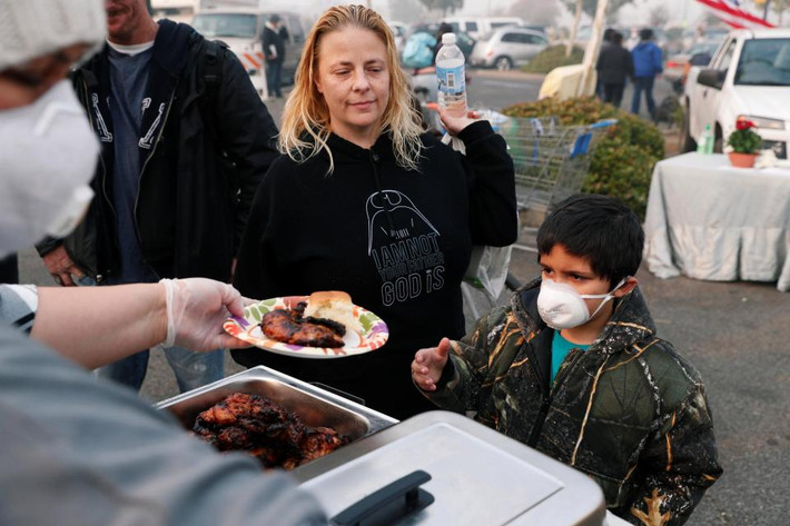 Người dân nhận đồ ăn được phân phát tại một khu trại tạm thời ở California. Ảnh: Reuters.