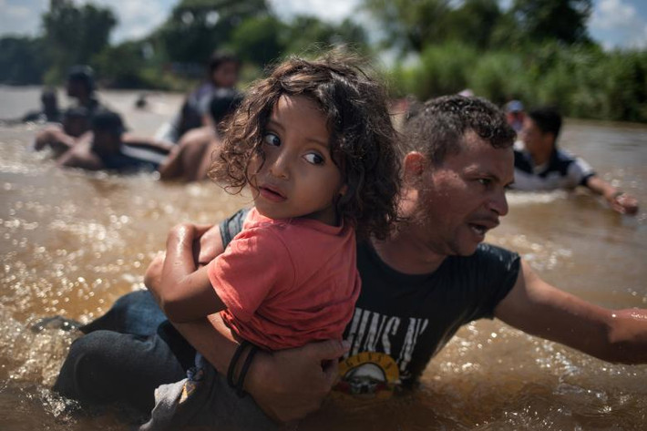 Luis Acosta bế bé Angel Jesus, 5 tuổi, đến từ Honduras, vượt sông Suchiate vào Mexico từ Guatemala ngày 29/10.