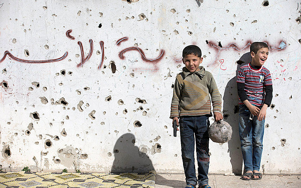 Thông báo về thời điểm các vòng đàm phán mới về Syria của ông Mistura được đưa ra chưa đầy một giờ sau khi lệnh ngừng bắt đầu có hiệu lực. Ảnh: Một bé trai cầm khẩu súng đồ chơi trong lúc chơi đá bóng với bạn ở thành phố Homs.