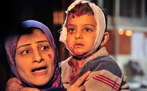 Hình ảnh một bé trai Syria bị thương tại bệnh viện ở Damascus hồi tuần trước. Thông báo về thời điểm các vòng đàm phán mới về Syria của ông Mistura được đưa ra chưa đầy một giờ sau khi lệnh ngừng bắt đầu có hiệu lực. Ảnh: Một bé trai cầm khẩu súng đồ chơi trong lúc chơi đá bóng với bạn ở thành phố Homs. Dòng chữ trên bức tường có nội dung “(Tổng thống) al-Assad của Syria).