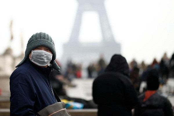 Một du khách đeo khẩu trang phía trước Tháp Eiffel ở Paris, Pháp, ngày 25/1.