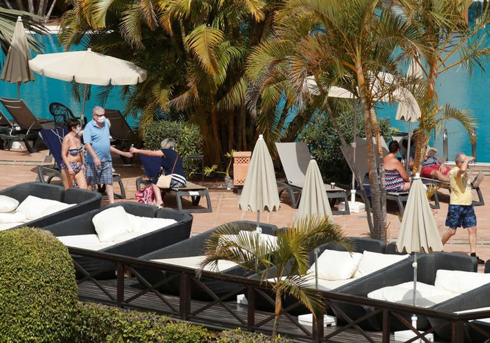 Các du khách đeo khẩu trang đi bộ gần bể bơi của khách sạn H10 Costa Adeje Palace thuộc đảo Tenerife, Tây Ban Nha, ngày 26/2.