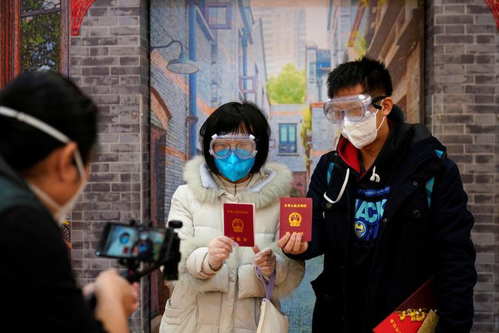 Jia, 29 tuổi, và vợ Su, 28 tuổi, đeo khẩu trang "khoe" giấy chứng nhận kết hôn vào ngày Valentine tại Thượng Hải, Trung Quốc.