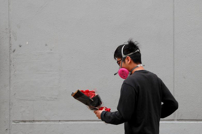 Một thanh niên đeo mặt nạ cầm bó hoa trong ngày Valentine ở Hong Kong, Trung Quốc.