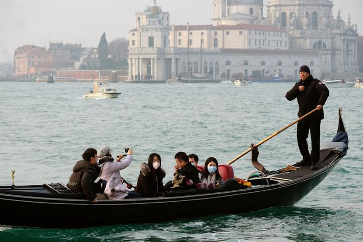 Các du khách đeo khẩu trang khi ngồi trên thuyền ngắm cảnh ở Venice, Italy, hôm 31/1.