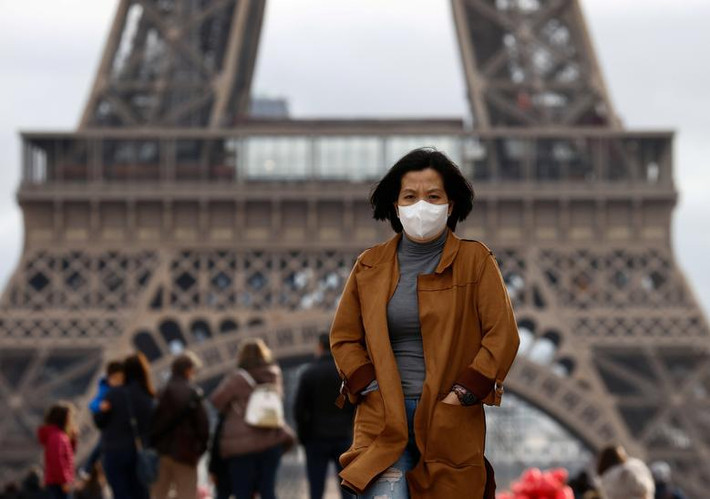 Người phụ nữ đeo khẩu trang đi bộ phía trước Tháp Eiffel ở Paris, Pháp, ngày 1/2.