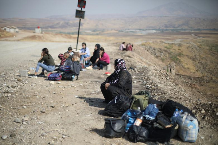 Một nhóm người Kurd ngồi chờ tại cửa khẩu Semalka, gần thành phố Derik (Syria), để vượt biên sang Iraq hôm 21/10.