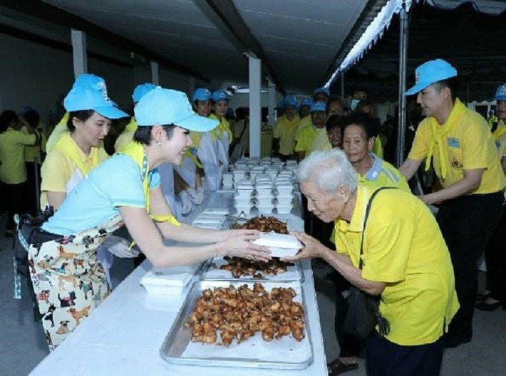 Bà Sineenat được nhìn thấy đeo tạp dề, xuống bếp nấu nướng với những người khác, tự tay phát những hộp cơm từ thiện cho người già.