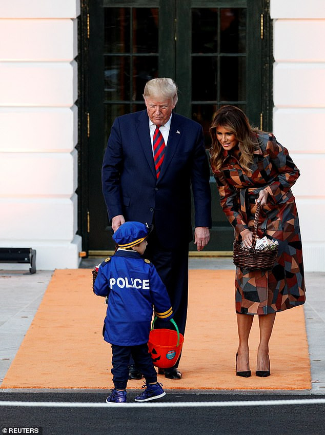 Tổng thống Trump chăm chú nhìn một cảnh sát tí hon cầm theo chiếc giỏ đựng kẹo.