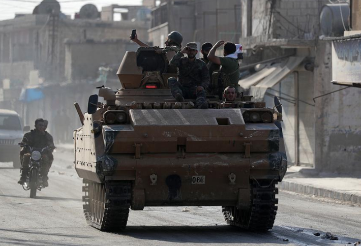 Nhóm quân nổi dậy trên một xe quân sự trong thị trấn Tal Abyad ngày 13/10. Ảnh: Reuters.