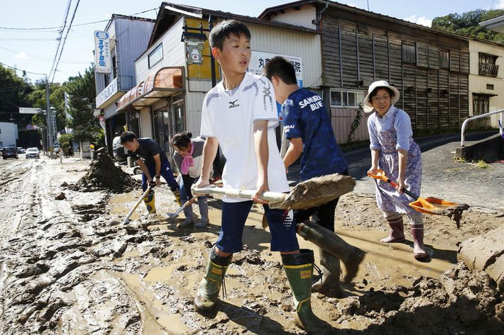 Người dân dọn dẹp con đường đầy bùn đất ở Marumori, tỉnh Miyagi, sau khi bão Hagibis đi qua. Ảnh: Reuters.