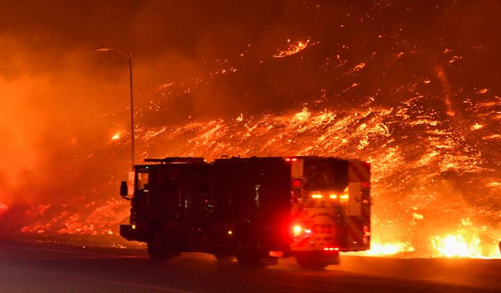 Xe cứu hỏa đi qua đám cháy rừng dữ dội ở Sylmar, California.