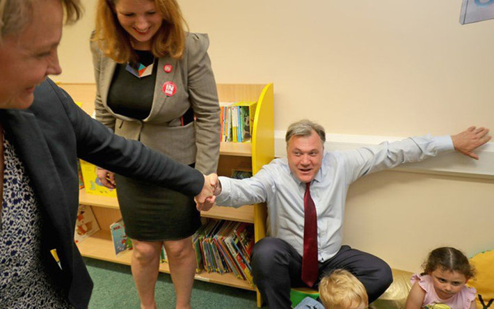 Nghị sỹ Anh Ed Balls lúng túng khi phải phải nhờ vợ kéo đứng dậy sau một buổi đọc chuyện cho các em nhỏ.