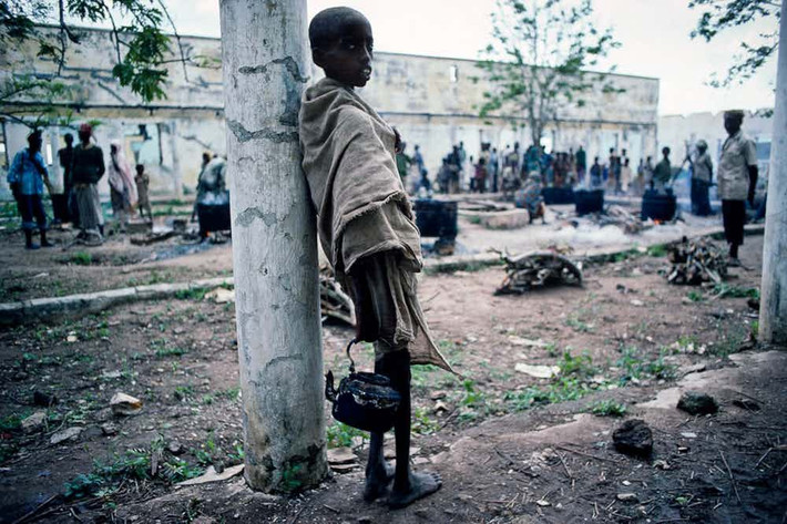 Trong cuộc nội chiến ở Somalia, nhiều dân thường đã phải rời bỏ nhà cửa đến các trại tị nạn và sống trong điều kiện vô cùng tồi tệ. Ảnh: Một em nhỏ trong thân hình gầy gò đứng bên ngoài một trại tị nạn cho dân thường sơ tán hồi tháng 7/1992.