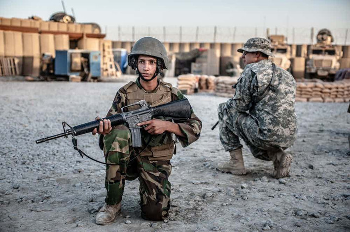 Một bé trai Afghanistan trong độ tuổi thanh thiếu niên học kỹ năng chiến đấu từ binh sĩ đặc nhiệm Mỹ. Đây là một trong những bức ảnh gây sốc về cuộc chiến Afghanistan.