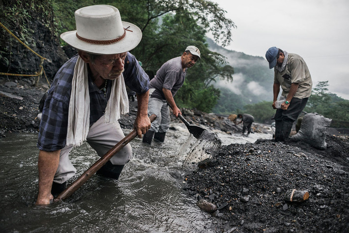 Một nhóm người dùng xẻng hoặc tay không đang cố gắng tìm những viên đá quý ở Colombia.