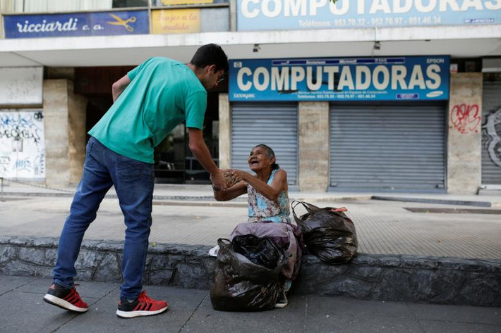 Tình nguyện viện Mariano Marquez phân phát súp cho một người phụ nữ vô gia cư trên đường phố Caracas ngày 12/3.