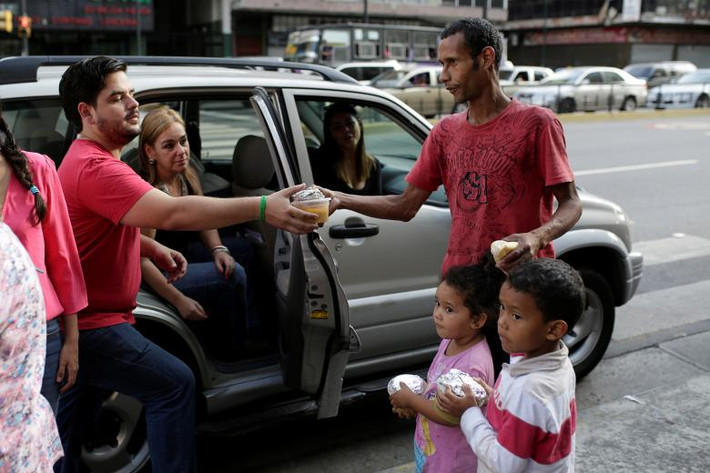 Diego Prada (trái) phân phát súp và bánh cho người dân trên đường phố ở Caracas ngày 12/3.