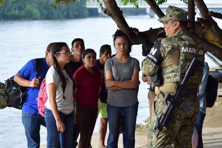 Một sĩ quan cảnh sát Mexico trao đổi với một nhóm người nhập cư bị chặn lại sau khi vượt sông Suchiate từ Tecun Uman, Guatemala, sang Ciudad Hidalgo, Mexico, ngày 16/6.