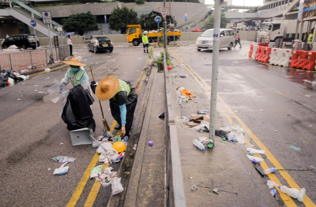 Nhân viên vệ sinh ở Hong Kong thu dọn rác thải, chai lọ vứt đầy trên đường phố ngày 13/6.