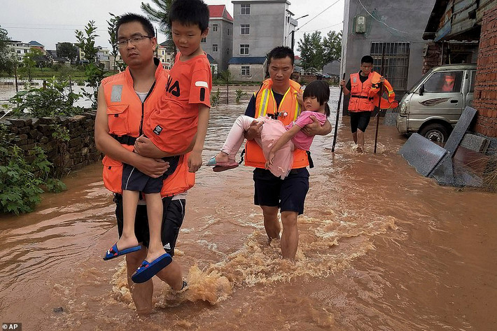 Lực lượng cứu hộ bế các em nhỏ ra khỏi khu vực ngập lụt ở Cát An, tỉnh Giang Tây. Ảnh: AP.