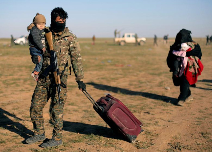 Thành viên SDF bế một em nhỏ gần làng Baghouz, tỉnh Deir Ezzor, ngày 1/3.