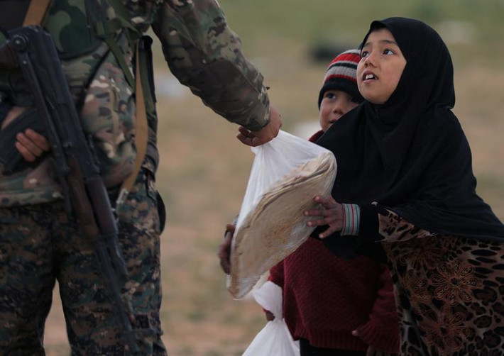 Một bé gái cầm túi bánh mì mà chiến binh SDF đưa cho gần ngôi làng Baghouz.
