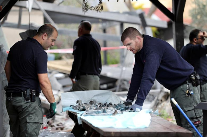 Cảnh sát Israel làm việc cạnh ngôi nhà bị hư hại ở phía bắc thủ đô Tel Aviv ngày 25/3. Ảnh: Reuters.