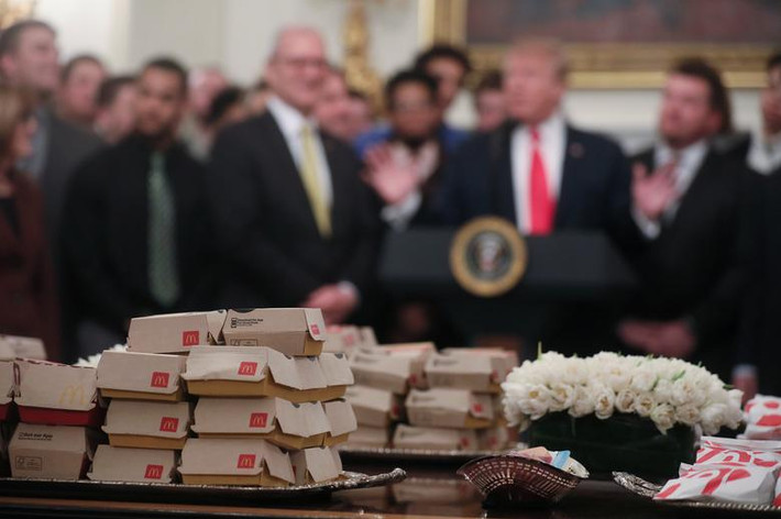 Bàn ăn với rất nhiều bánh hamburger McDonald, sandwich gà Chick-fil-A và nhiều loại đồ ăn nhanh khác.