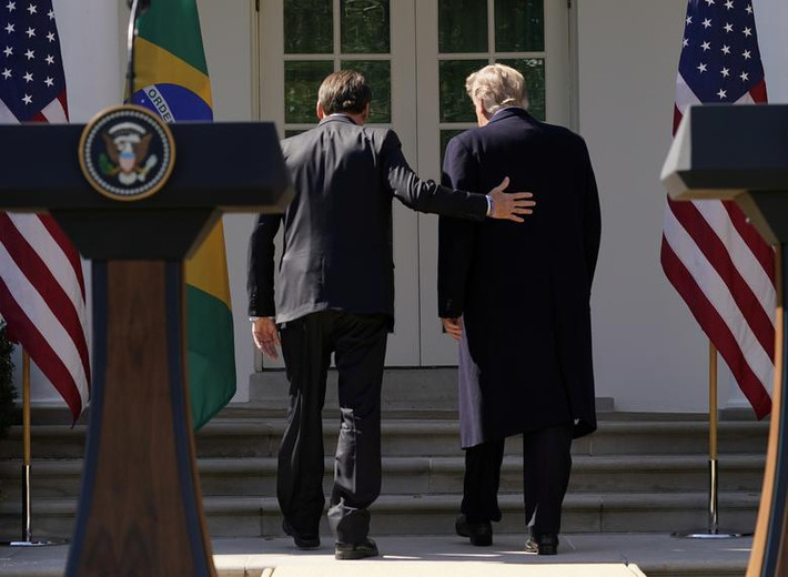 Tổng thống Brazil Jair Bolsonaro đặt tay phía sau lưng ông Trump đi vào trong sau khi kết thúc cuộc họp báo.