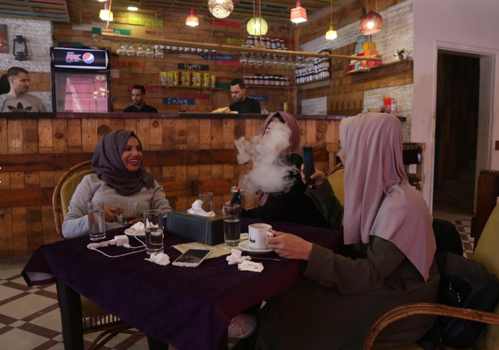 Saly Abu Amra (trái), một sinh viên đại học 23 tuổi, ngồi nói chuyện với bạn trong quán cà phê.