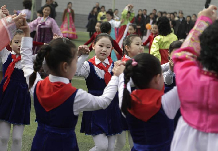 Các em nhỏ ca múa bên ngoài một điểm bỏ phiếu ở Bình Nhưỡng. Ảnh: AP.