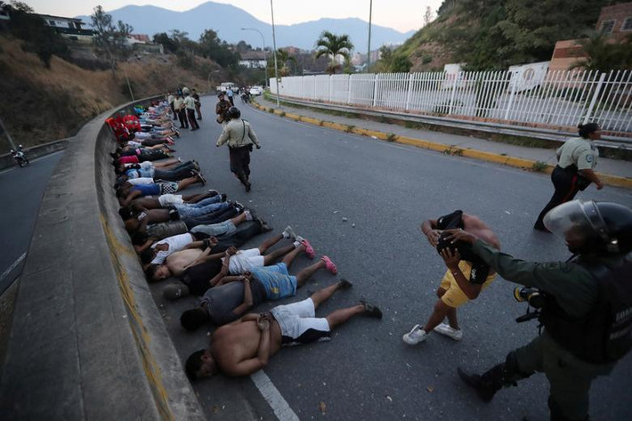 Một số người bị bắt giữ nằm xuống đường ở thủ đô Venezuela.