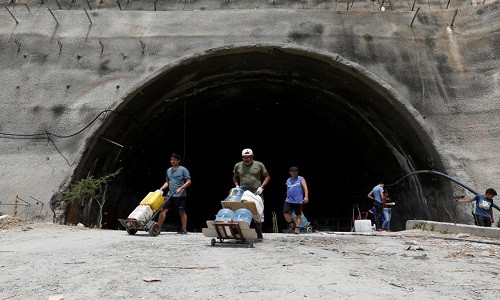 Những người đàn ông đẩy chiếc xe chở đầy bình nước tại thủ đô Caracas ngày 13/3.