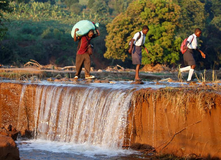 Người đàn ông vác bao tải đựng hàng viện trợ đi qua sông ở Chipinge, Zimbabwe, ngày 26/3/2019.