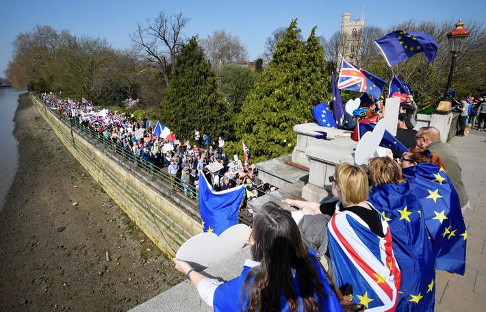 Một người biểu tình phản đối Brexit mang theo lá cờ EU đứng nhìn đoàn người ủng hộ Brexit tuần hành dọc sông Thames ở London ngày 29/3.
