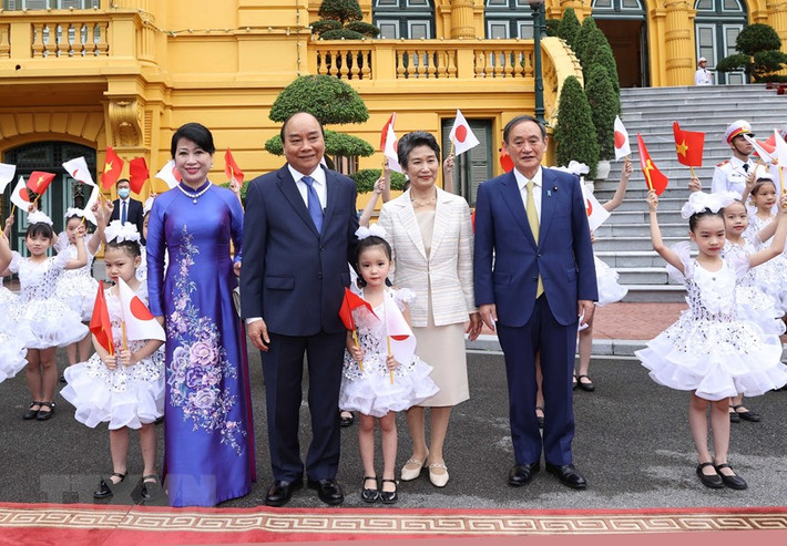 Thủ tướng Nguyễn Xuân Phúc và Phu nhân cùng Thủ tướng Nhật Bản Suga Yoshihide và Phu nhân với thiếu nhi Hà Nội tại Lễ đón. (Ảnh: Thống Nhất/TTXVN)
