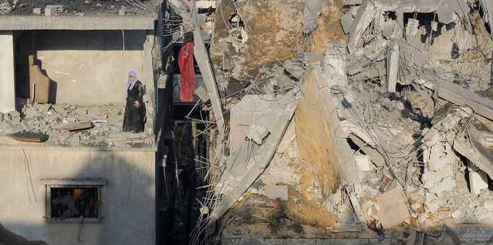 Người phụ nữ Palestine đứng trong căn phòng toàn gạch vỡ của một tòa nhà ở Khan Younis, ngày 6/12.