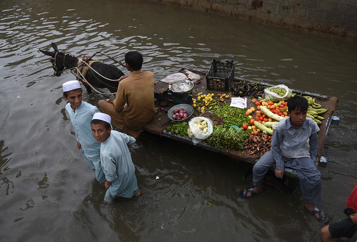Người bán hàng đi qua con phố ngập nước ở Karachi. Mưa lớn làm đảo lộn cuộc sống của người dân địa phương những ngày qua.