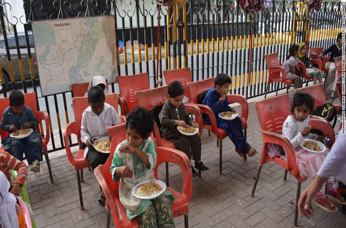 Các em học sinh ăn món truyền thống trong giờ ăn trưa tại Trường Karachi Footpath ở tỉnh Sindh, Pakistan. Theo CNN, ngôi trường này cung cấp bữa ăn miễn phí cho toàn bộ học sinh.