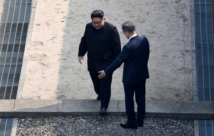 Khoảnh khắc Chủ tịch Triều Tiên Kim Jong-un bước qua đường phân giới ở khu phi quân sự DMZ giữa hai miền trước sự đón tiếp của Tổng thống Hàn Quốc Moon Jae-in. Ảnh: Reuters.